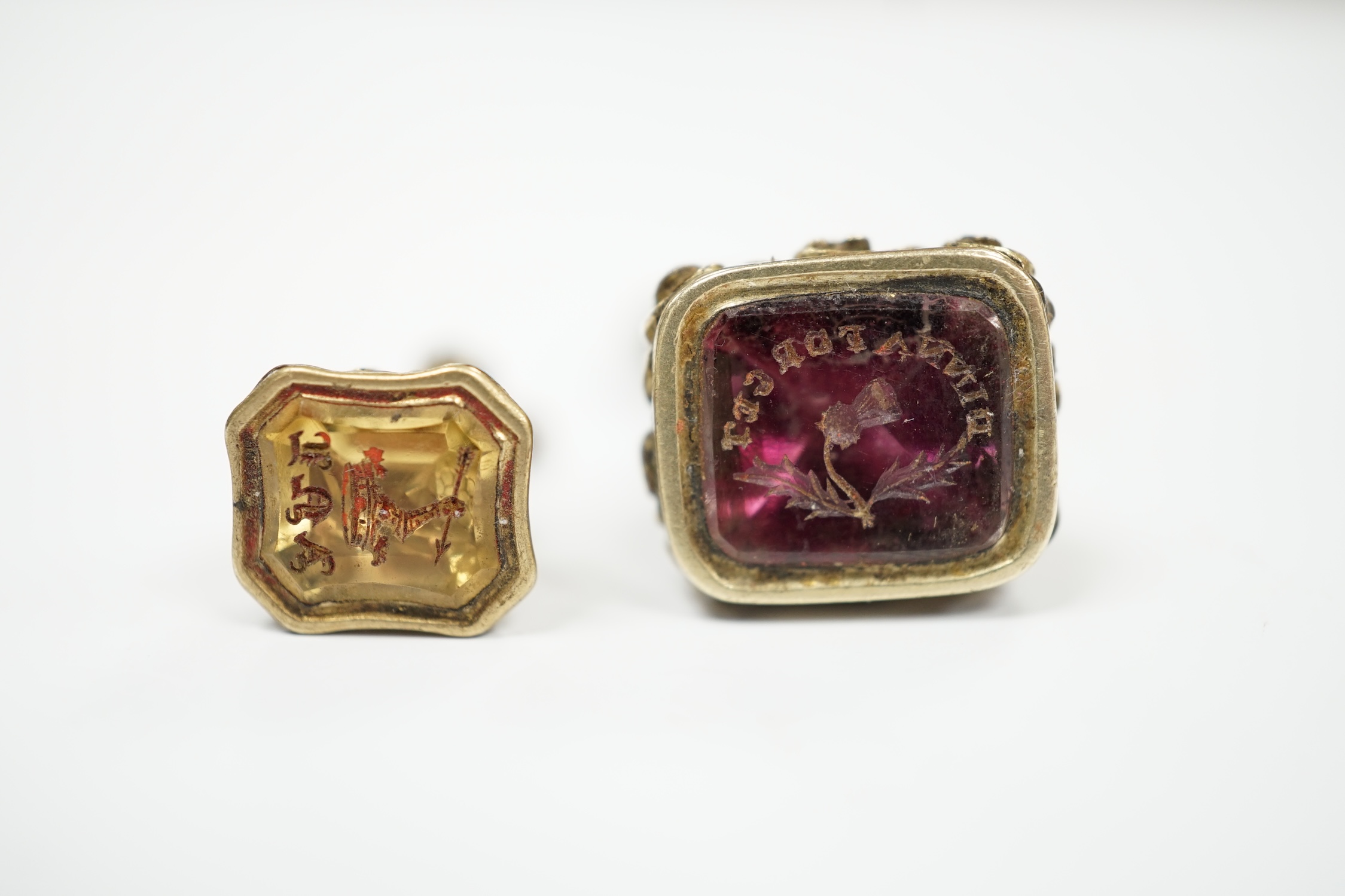 Two 19th century yellow metal overlaid and gem set fob seals, the largest with matrix carved with thistle and motto, 25mm.